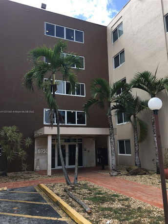 Front view of a multi-story building with palm trees at the entrance.