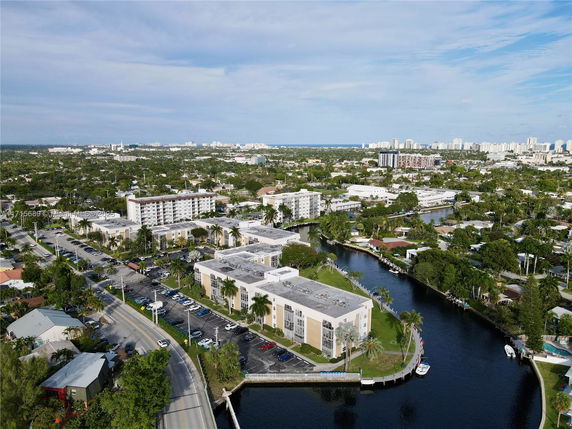 Aerial view of a residential area with buildings and waterways, surrounded by green spaces and roads.