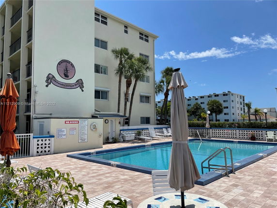 View of a multi-story residential building with a swimming pool in the foreground.