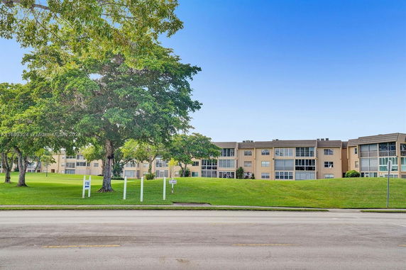 Front view of a multi-story building with multiple windows and a wide lawn.