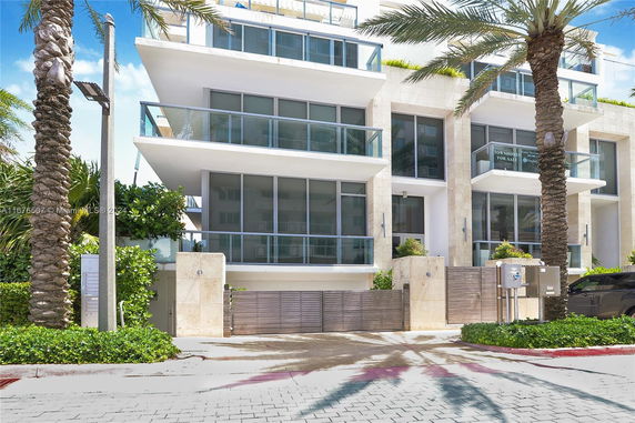 Front view of a modern multi-story residential building with glass balconies.