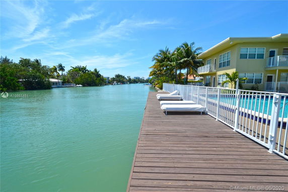 Outdoor view of a waterway with a building and swimming pool in the background.