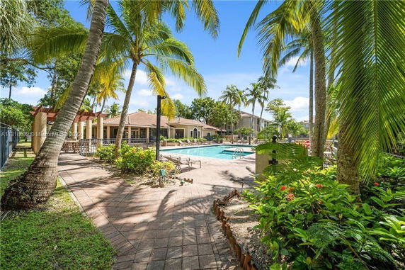Outdoor swimming pool area surrounded by palm trees and a landscaped garden.