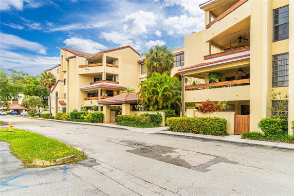 Front view of a multi-story apartment building with balconies and plants.