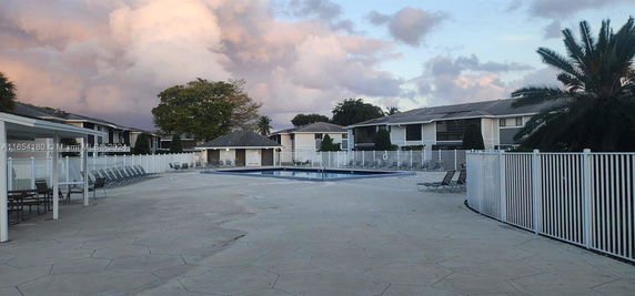 Outdoor view of a swimming pool area with nearby residential buildings.