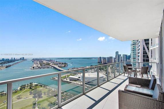 Panoramic view from a high-rise balcony overlooking a cityscape and waterfront area.