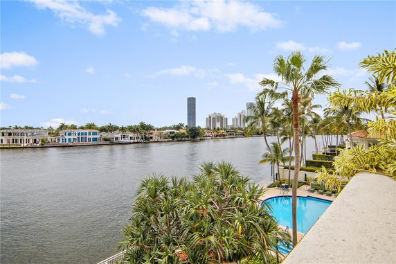 View of a waterway with residential buildings and palm trees.