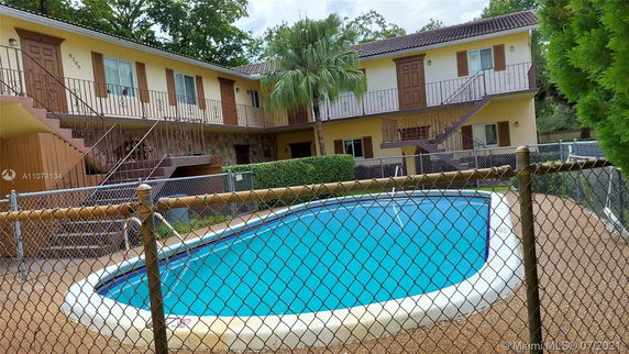 Outdoor swimming pool area with a two-story building in the background.