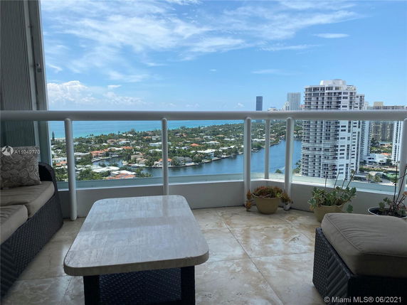 Panoramic view from a high-rise balcony overlooking a cityscape and waterfront.