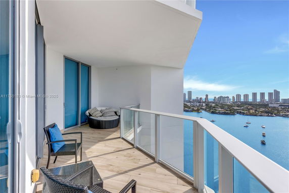 Balcony with seating and a view of water and cityscape.