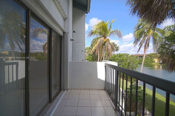 View from a balcony overlooking tropical trees and a small body of water.