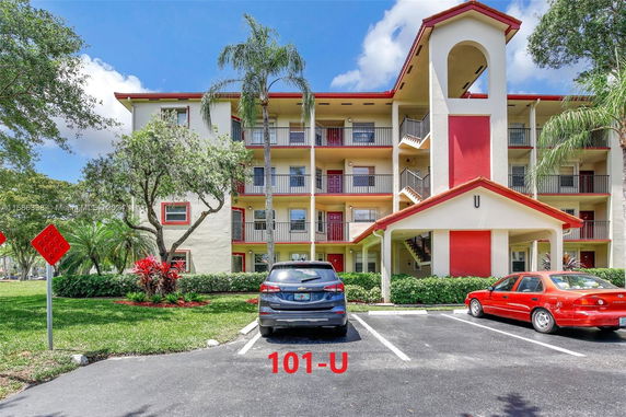 Front view of a multi-story residential building with exterior stairs and red accents.