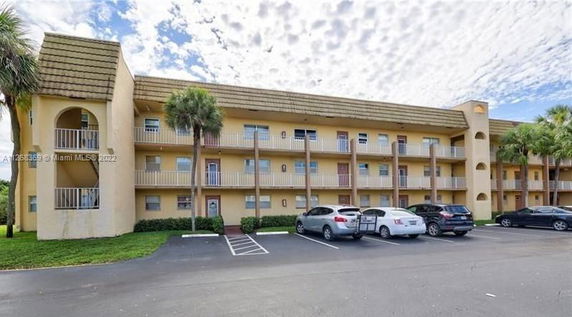 Front view of a three-story residential building with balconies and parking area.