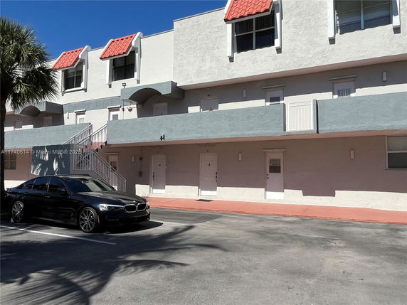 Parking area in front of a multi-story building with a modern design.