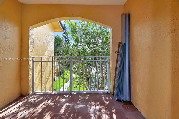 View from a balcony showing a garden area with trees visible through a railing.