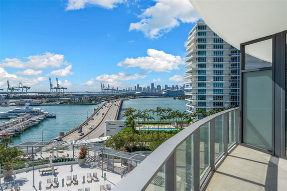 Panoramic view from a balcony overlooking a bridge, water body, and skyscrapers.