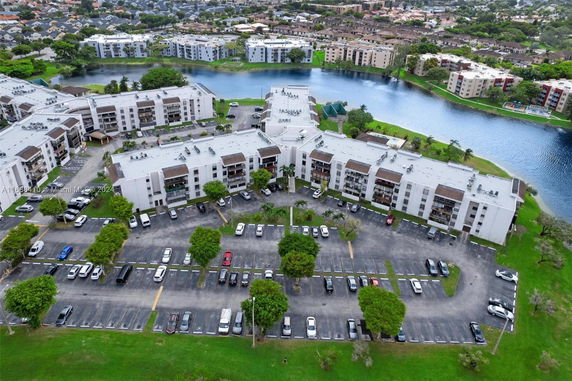 Aerial view of a residential complex with multiple apartment buildings, parking lots, and a nearby water body.