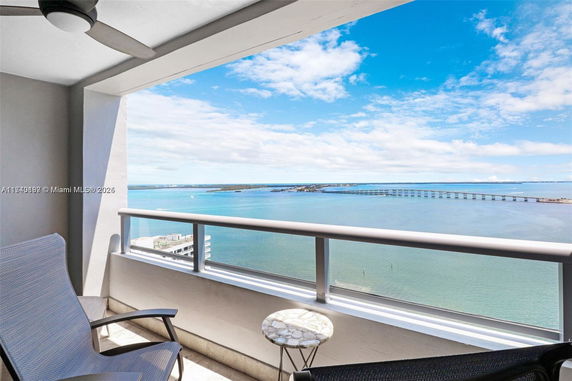 Balcony view overlooking a large body of water and a distant bridge with clear blue skies.