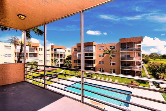 View from a balcony overlooking apartment buildings and a swimming pool.