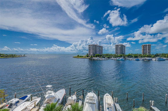View over water towards three high-rise buildings with boats docked in the foreground.