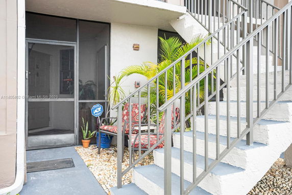 Front view of a building entrance with stairs and a seating area.