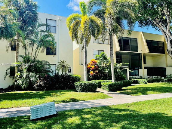 Front view of a two-story building with large windows and palm trees in the front.