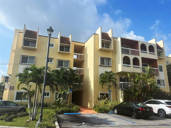 Front view of a multi-story apartment building with balconies and arched openings.