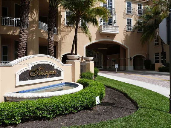 Front view of a multi-story building with an archway entrance and a fountain.