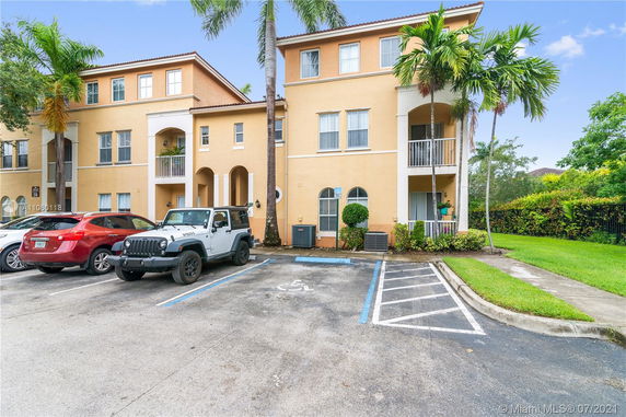 Outdoor view of a multi-story residential building with parking spaces in front.