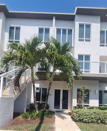 Front view of a modern multi-story residential building with a staircase and large windows.