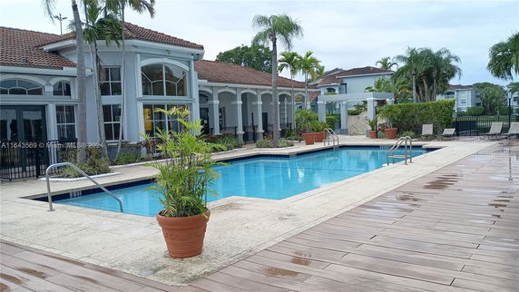 Outdoor swimming pool area next to a building with large windows and arches.