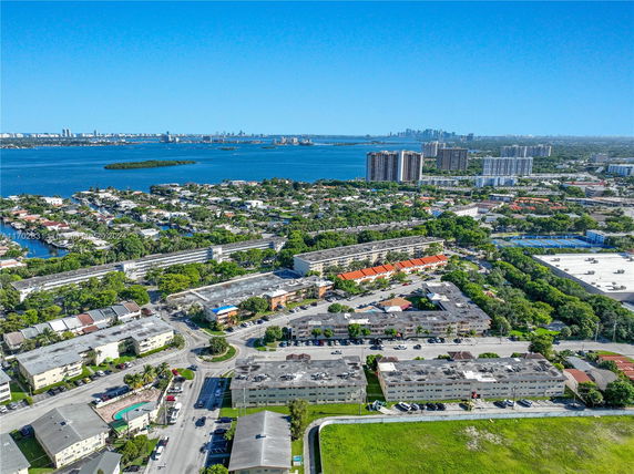 Aerial view of a residential area with multiple apartment buildings and a large body of water in the background.