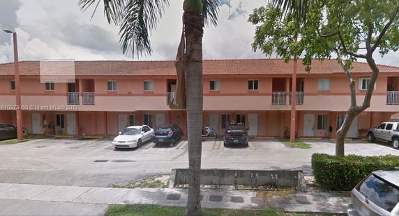 Front view of a two-story apartment building with parking spaces.