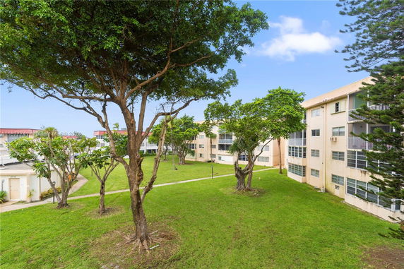 View of apartment buildings and green lawn area with trees.