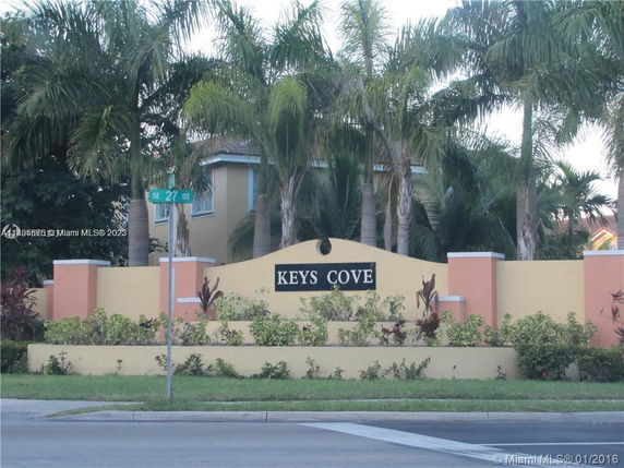 Front view of Keys Cove entrance with landscaping and palm trees.