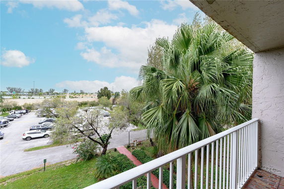 Balcony view overlooking parking area and greenery.
