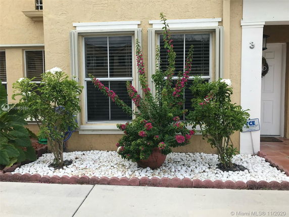 Front view of a house with a small garden decorated with white rocks and flowering plants.