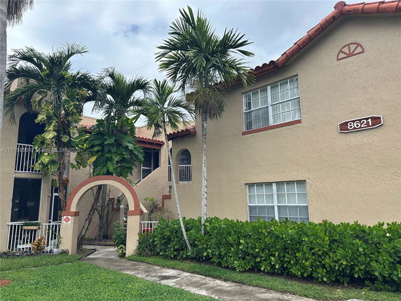 Front view of a two-story residential building with an arched entrance and red-tiled roof.