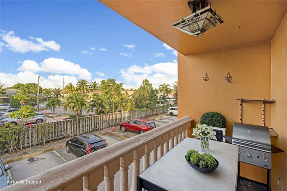 View from a balcony showing cars parked and greenery in a residential area.