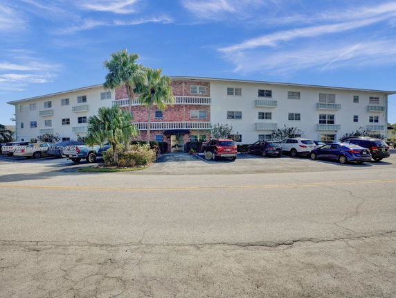 Front view of a three-story residential building with parking spaces in front.