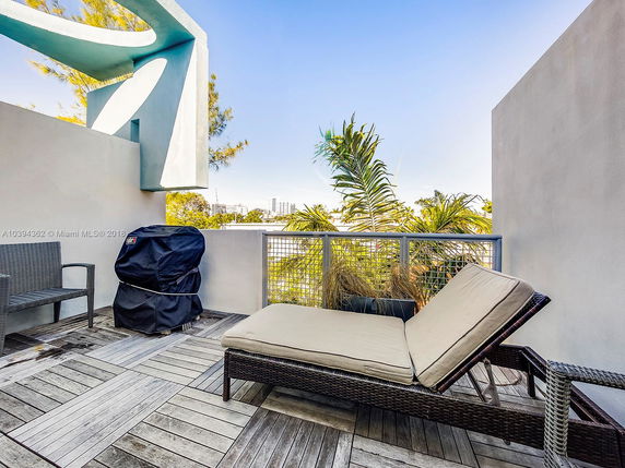 Rooftop area with outdoor seating and a grill, surrounded by modern architectural elements and plants.