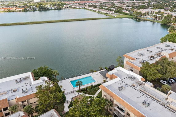 Aerial view of buildings with a swimming pool and a body of water in the background.