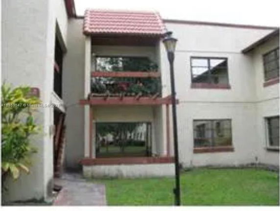 Front view of a two-story building with balconies and a tiled roof.
