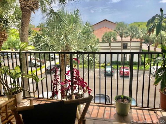 View from a balcony showing a parking area, palm trees, and adjacent buildings.