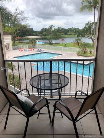 View from a balcony showing a swimming pool and a lake in the background.