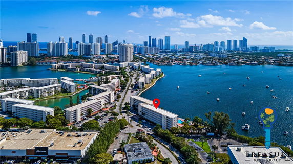 Aerial panoramic view of a coastal cityscape with high-rise buildings, waterfront, and surrounding residential areas.