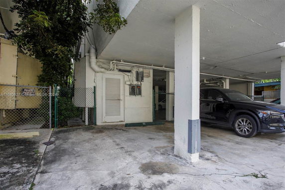 Outdoor parking area with a parked car and a gated utility section.