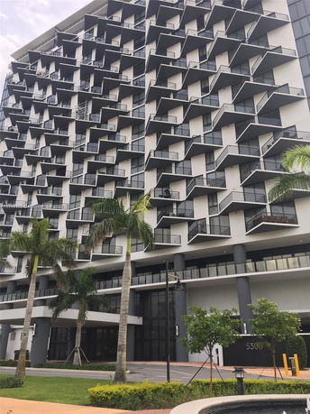 Front view of a modern multi-story building with unique balcony designs.