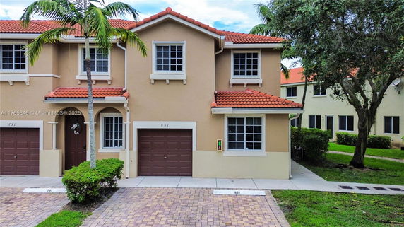 Front view of a two-story townhouse with a brown garage and red tile roof.