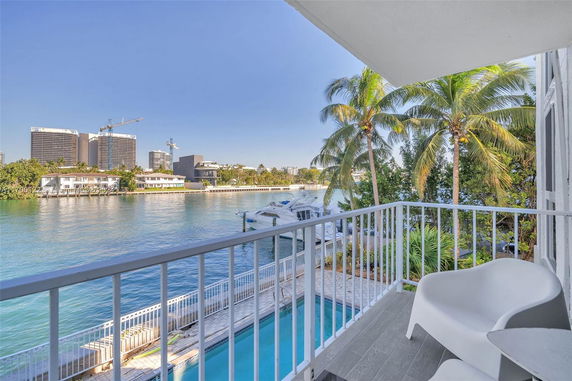 View from a balcony overlooking a waterway with buildings and palm trees in the distance.